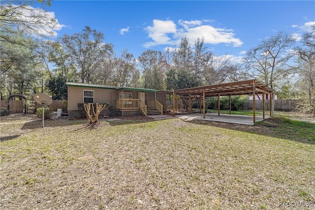 exterior space featuring a detached carport, metal roof, a lawn, a patio, and fence