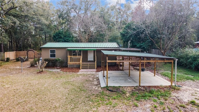 exterior space with stucco siding, fence, covered porch, metal roof, and a yard