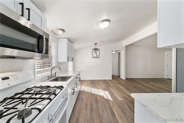 kitchen featuring white cabinets, hanging light fixtures, stainless steel microwave, vaulted ceiling, and white gas range