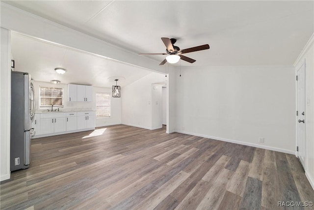 unfurnished living room featuring wood finished floors, baseboards, a sink, and lofted ceiling