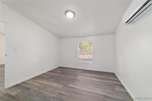 empty room featuring baseboards, wood finished floors, and an AC wall unit