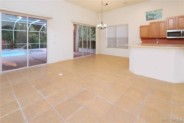 kitchen featuring pendant lighting, light tile patterned flooring, sink, and a chandelier