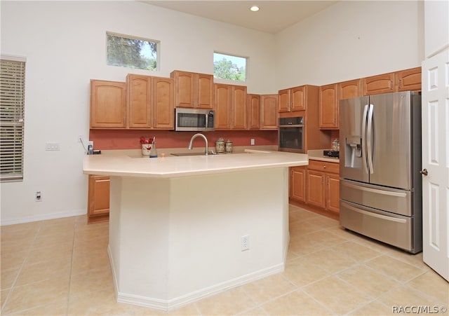 kitchen featuring light tile patterned flooring, a towering ceiling, sink, and appliances with stainless steel finishes