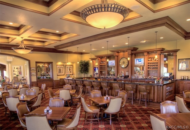 dining room featuring beam ceiling, bar, coffered ceiling, and ornamental molding