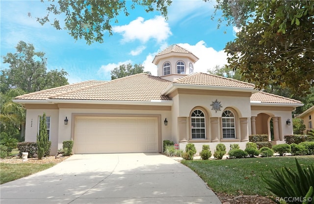 mediterranean / spanish house with a garage and a front lawn