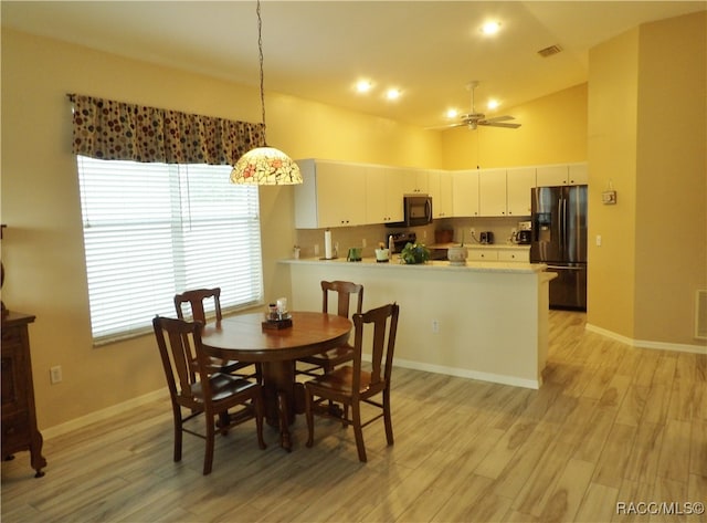 dining space with light wood-type flooring, ceiling fan, and lofted ceiling