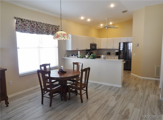 dining area featuring ceiling fan, light wood-type flooring, and vaulted ceiling