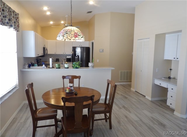 dining area with light wood-type flooring and high vaulted ceiling