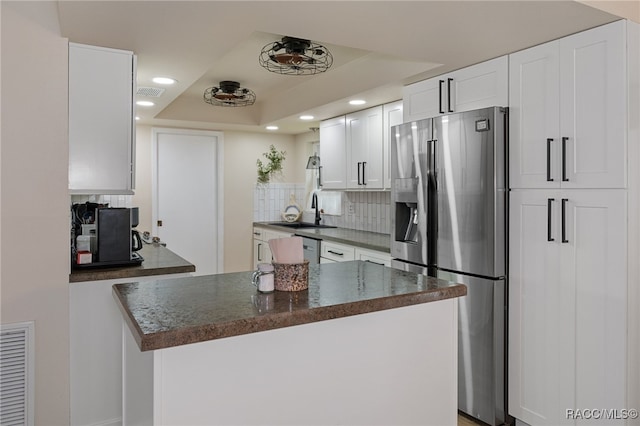 kitchen featuring white cabinetry, sink, a raised ceiling, stainless steel refrigerator with ice dispenser, and decorative backsplash