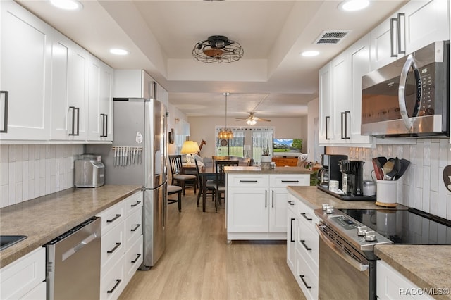 kitchen with white cabinets, ceiling fan, light wood-type flooring, and stainless steel appliances