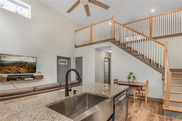 kitchen featuring dishwasher, sink, hardwood / wood-style flooring, a high ceiling, and ceiling fan