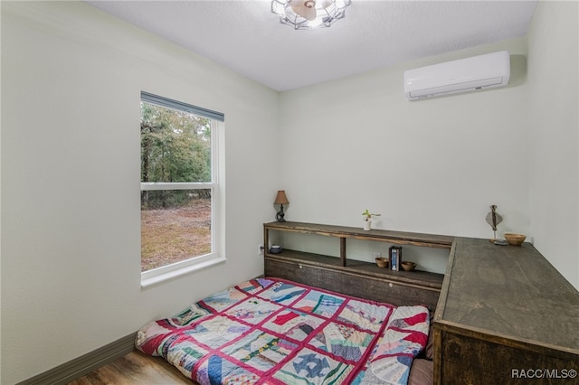 bedroom with hardwood / wood-style flooring and a wall mounted AC