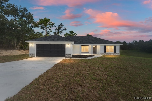 ranch-style house featuring a garage and a lawn