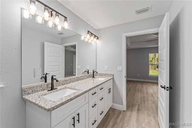 bathroom featuring vanity, wood-type flooring, a textured ceiling, and ceiling fan