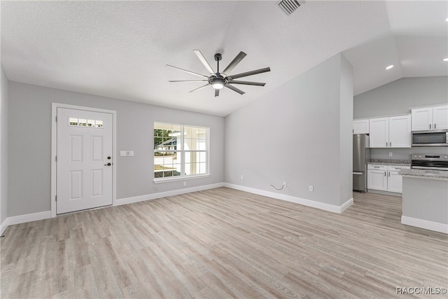 unfurnished living room featuring ceiling fan, light hardwood / wood-style floors, a textured ceiling, and vaulted ceiling