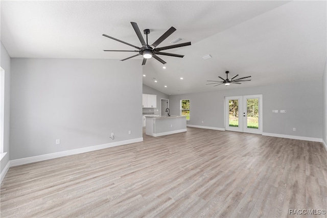 unfurnished living room featuring french doors, light wood-type flooring, vaulted ceiling, and sink