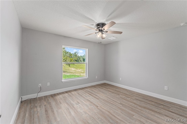 spare room featuring ceiling fan, light wood-type flooring, and a textured ceiling