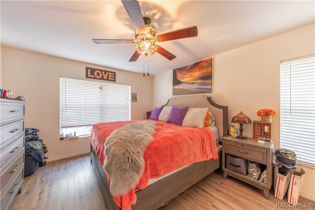 bedroom with multiple windows, light hardwood / wood-style floors, and ceiling fan