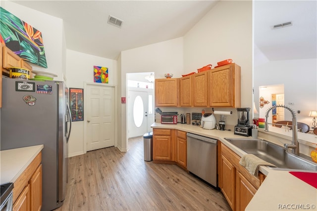 kitchen with light wood-type flooring, stainless steel appliances, vaulted ceiling, and sink