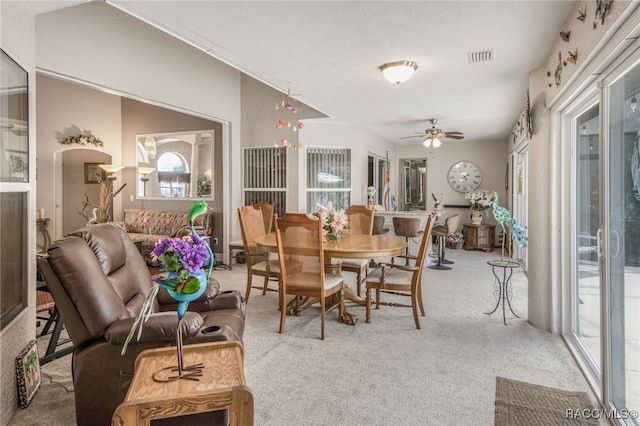 dining room featuring ceiling fan, light colored carpet, and a textured ceiling