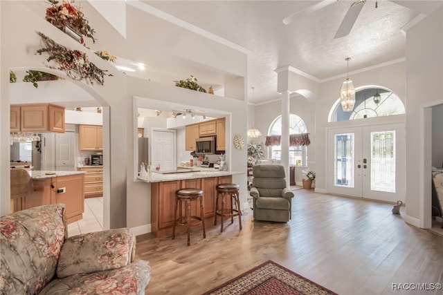 living room featuring light wood-type flooring, a textured ceiling, a high ceiling, and french doors