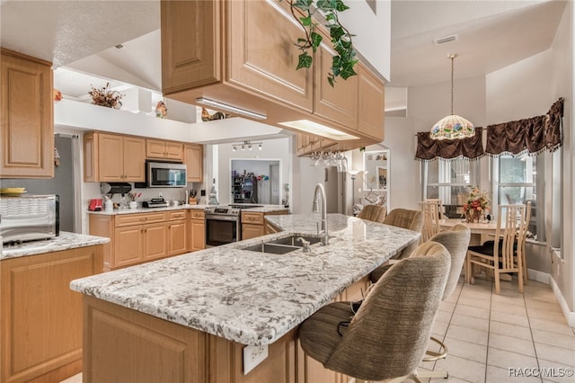 kitchen featuring sink, stainless steel appliances, vaulted ceiling, a breakfast bar, and light tile patterned floors