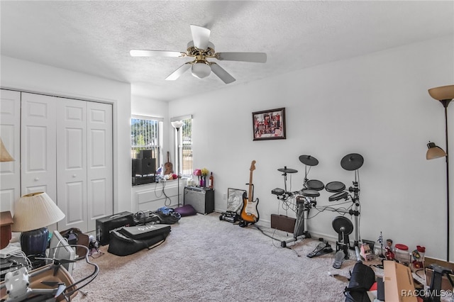 exercise area featuring carpet flooring, ceiling fan, and a textured ceiling