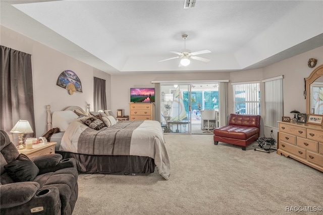 bedroom with carpet floors, access to outside, ceiling fan, and a tray ceiling