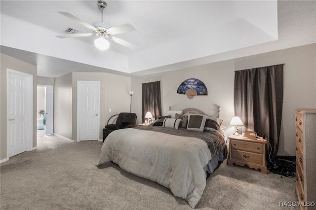 bedroom featuring light colored carpet, ceiling fan, and a tray ceiling