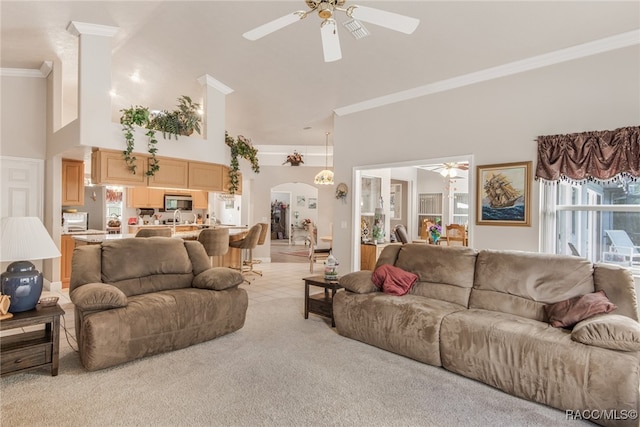 carpeted living room featuring ceiling fan, a towering ceiling, and ornamental molding