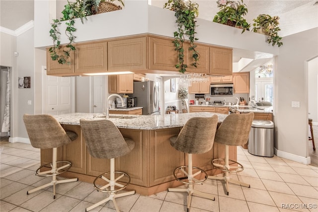 kitchen with appliances with stainless steel finishes, a kitchen breakfast bar, crown molding, sink, and light tile patterned floors