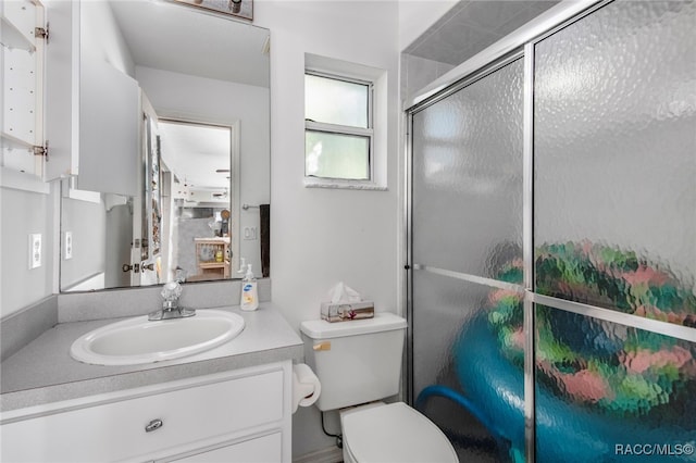 bathroom with vanity, toilet, and a shower with shower door