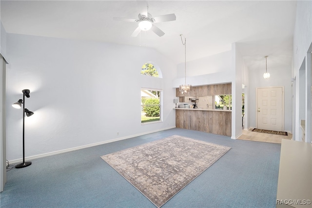 carpeted living room with ceiling fan with notable chandelier and lofted ceiling