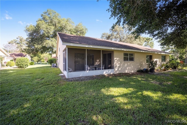 rear view of property with a sunroom and a lawn