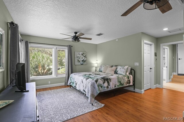 bedroom with ceiling fan, hardwood / wood-style floors, and a textured ceiling