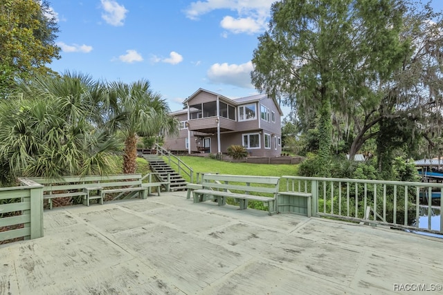 wooden terrace with a yard, a water view, and a sunroom