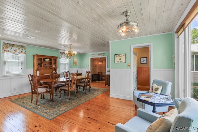 dining area with hardwood / wood-style flooring, a notable chandelier, ornamental molding, and a wealth of natural light