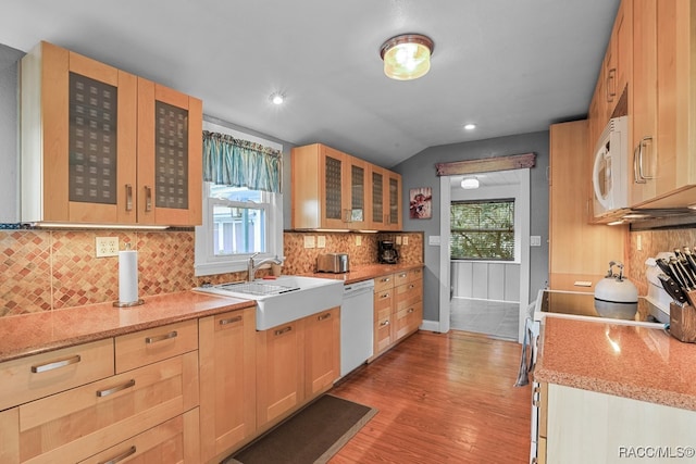 kitchen featuring lofted ceiling, white appliances, sink, light hardwood / wood-style flooring, and light stone countertops