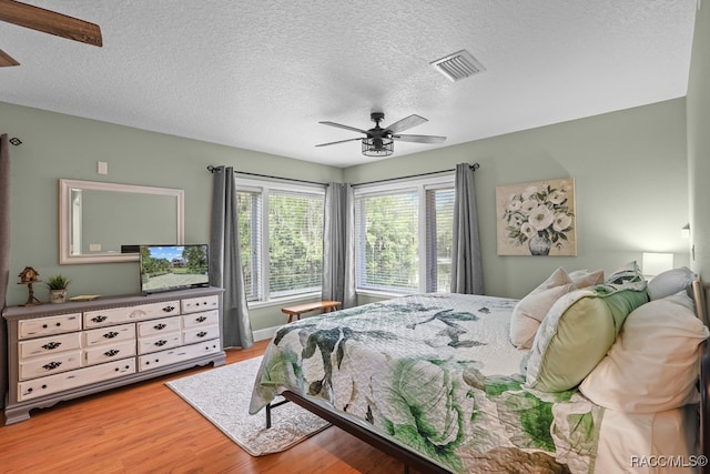 bedroom featuring ceiling fan, hardwood / wood-style floors, and a textured ceiling