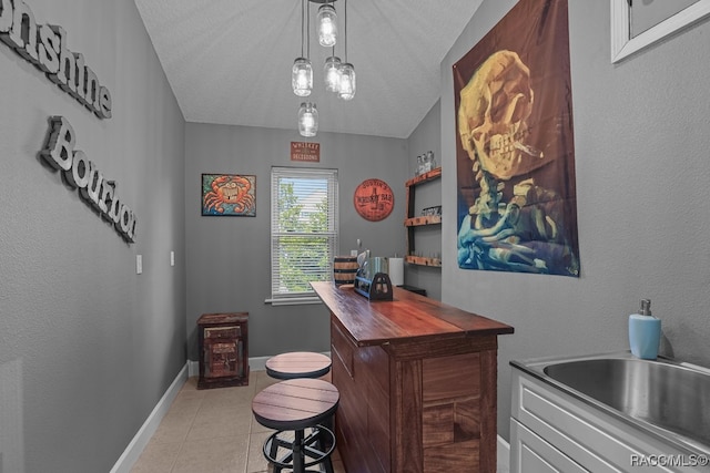 bar with sink, wood counters, pendant lighting, a textured ceiling, and light tile patterned floors