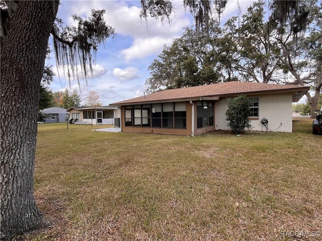 rear view of house featuring a sunroom and a lawn