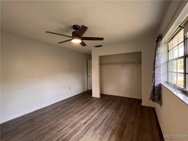 unfurnished bedroom featuring dark wood-style flooring, a closet, visible vents, a ceiling fan, and a textured ceiling