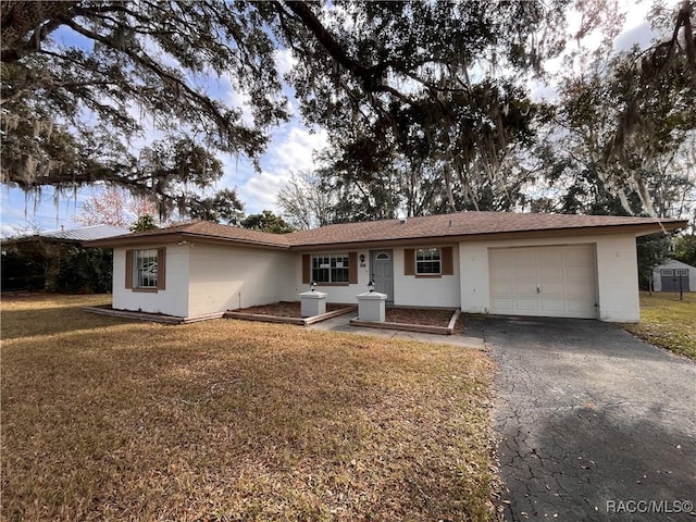 single story home featuring aphalt driveway, concrete block siding, a front lawn, and an attached garage