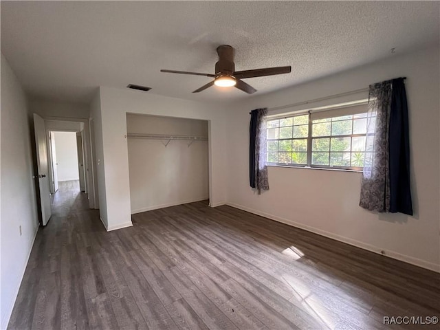 unfurnished bedroom with a textured ceiling, ceiling fan, baseboards, a closet, and dark wood finished floors