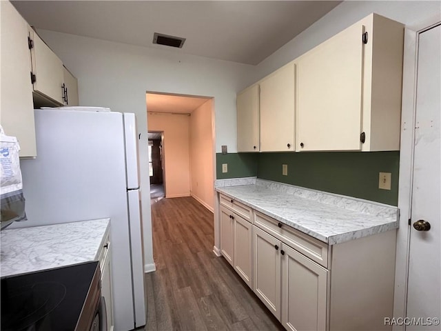 kitchen with dark wood-style floors, light countertops, visible vents, and white cabinetry