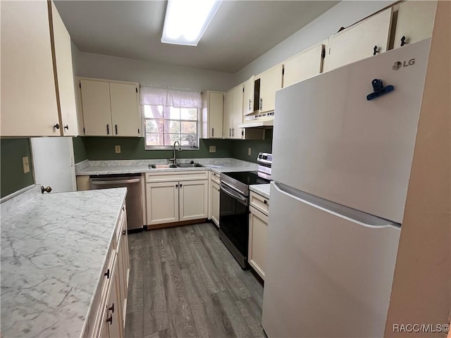 kitchen with dark wood-style floors, appliances with stainless steel finishes, light countertops, under cabinet range hood, and a sink