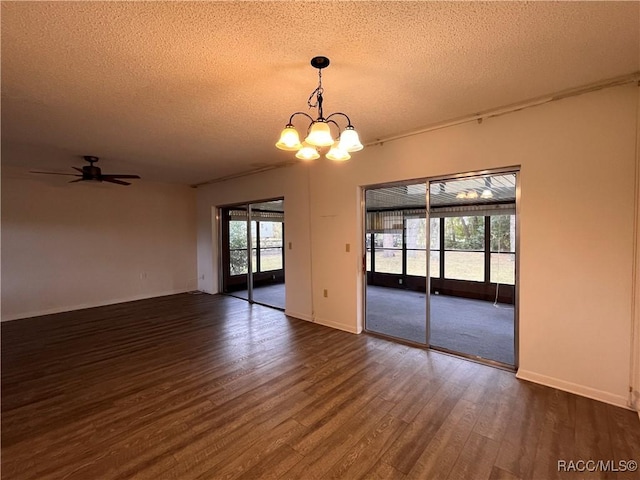 empty room featuring a textured ceiling, dark wood-type flooring, ceiling fan with notable chandelier, and baseboards