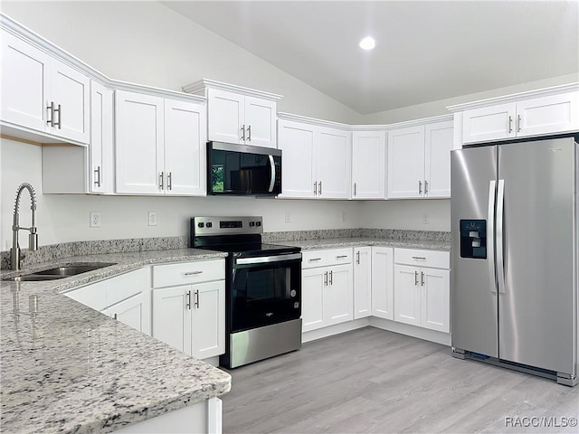22777 SW Beach Blvd, Dunnellon, FL 34431 - kitchen featuring stainless steel appliances, a sink, lofted ceiling, white cabinetry, and light stone counters
