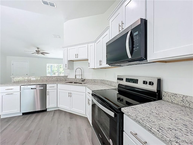 22777 SW Beach Blvd, Dunnellon, FL 34431 - kitchen with stainless steel appliances, a sink, white cabinets, and light stone countertops