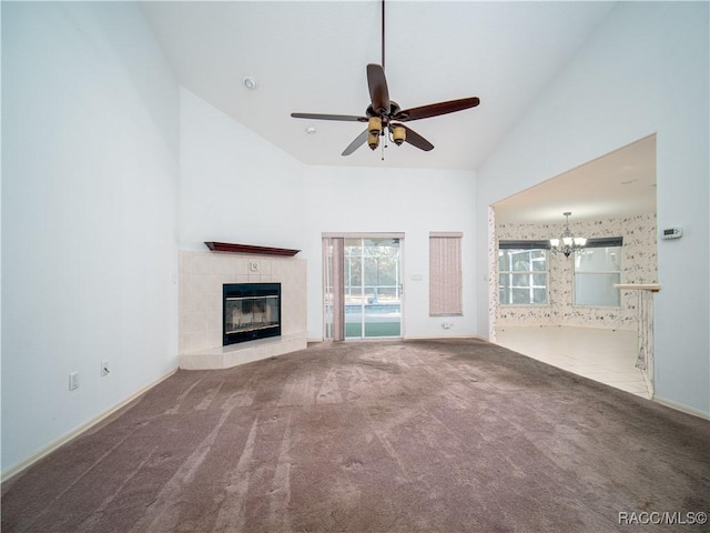 unfurnished living room with a tiled fireplace, ceiling fan with notable chandelier, carpet floors, and high vaulted ceiling